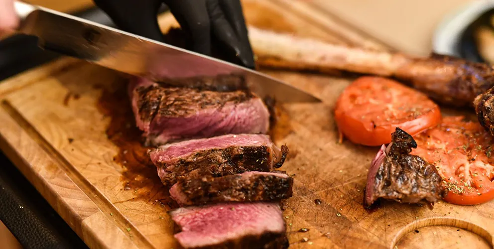 Gegrilltes Steak wird auf dem Holzbrett aufgeschnitten